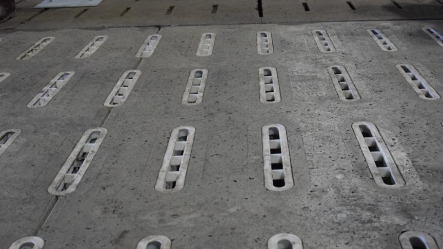 Vooraan op de foto is het FlexiFlor-beluchtingsrooster te zien met de verzonken ventilatieopeningen waar de AirSlots in zitten. Achteraan op foto is de traditionele roostervloer van een aardappelbewaarplaats zichtbaar.